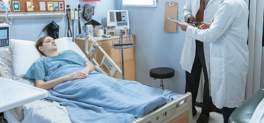Doctors attending to a patient in a hospital bed — health insurance cover